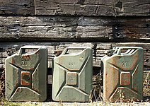 Drei Benzinkanister vor einer Holzwand