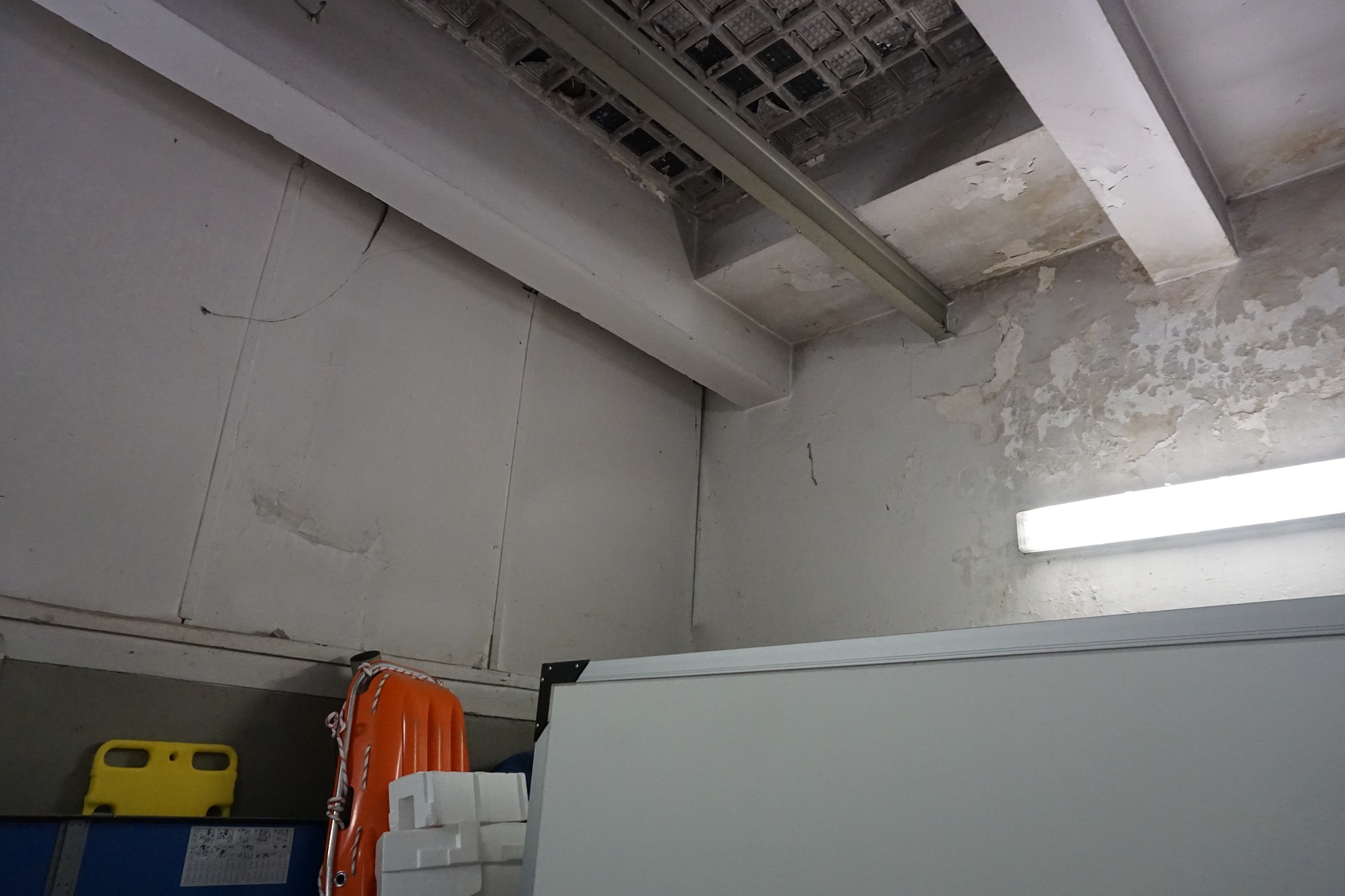 Blick auf eine Wand in der Fahrzeughalle, der Putz und die Farbe blättern ab